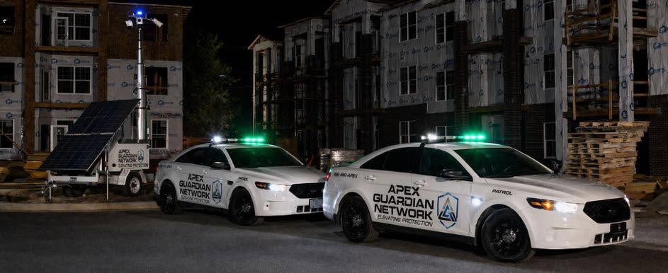 Two AGN patrol vehicles and a mobile camera trailer covering an apartment construction site at night