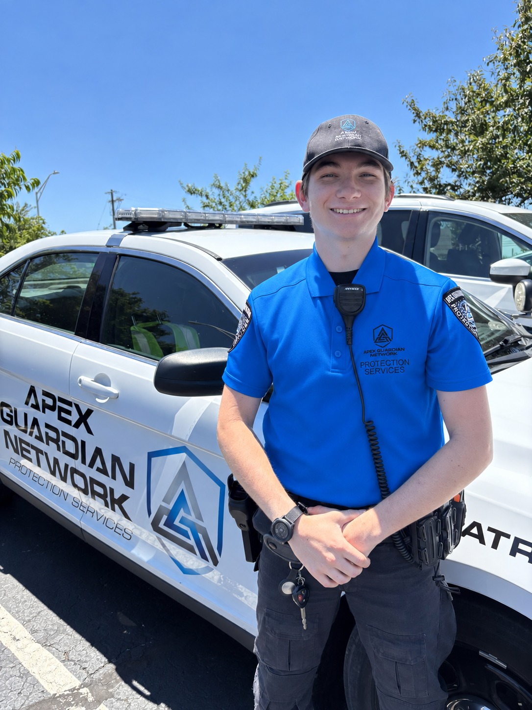 AGN unarmed officer in uniform polo standing by a patrol vehicle during the day
